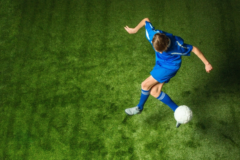 Young boy with soccer ball doing flying kick